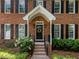 Close-up of a charming front door with brick steps, black railing, and manicured landscaping at 8004 Gabriels Bend Dr, Raleigh, NC 27612