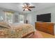 Bedroom features a ceiling fan, wood floors, floral bedding, and a dresser with a large television on top at 8004 Gabriels Bend Dr, Raleigh, NC 27612