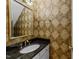 Stylish powder room featuring a granite countertop, gold accents and designer wallpaper at 8004 Gabriels Bend Dr, Raleigh, NC 27612