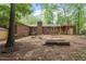 Backyard view of a brick home showing the exterior, chimney, and landscaping with wooded area and garden bed at 809 Valerie Dr, Raleigh, NC 27606