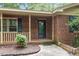 Close-up of the front entrance featuring brick columns, a black door, and manicured landscaping at the front of the home at 809 Valerie Dr, Raleigh, NC 27606