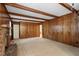 Large living room featuring a wood paneled wall, exposed ceiling beams and a fireplace at 809 Valerie Dr, Raleigh, NC 27606