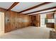 Large living room featuring a wood paneled wall, exposed ceiling beams and a built in desk at 809 Valerie Dr, Raleigh, NC 27606
