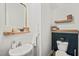 A powder room with updated sink, framed mirror, and wood-look shelves provides charming, accessible convenience at 947 Weatherby Ln, Creedmoor, NC 27522