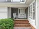 Close-up of the entrance featuring brick steps, a white rocking chair, and a paneled front door at 10 Marchmont Ct, Durham, NC 27705