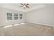 Spacious bedroom featuring a tray ceiling, ceiling fan, and three large windows letting in natural light at 1127 Timbercut Dr, Durham, NC 27703