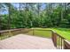 A backyard features a wooden deck, green lawn, and bordered by lush trees at 117 Garden Oaks Dr, Smithfield, NC 27577