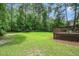 Green backyard view showcasing spacious lawn bordered by lush greenery from wooden deck at 117 Garden Oaks Dr, Smithfield, NC 27577
