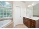 Bright bathroom with soaking tub, arched window, and dark wood vanity at 117 Garden Oaks Dr, Smithfield, NC 27577