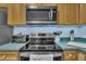 Modern kitchen features stainless steel appliances, including a microwave, oven, and stove top, complemented by wooden cabinetry at 120 Feezor Ct, Clayton, NC 27527