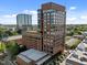 Brick exterior of a high-rise building with many windows and a green roof, set against a blue sky and green trees at 122 N Harrington St # 1555, Raleigh, NC 27603