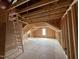 View of an unfinished attic showing exposed wooden beams, insulation, and a ladder at 155 Cherry Bark Dr, Youngsville, NC 27596