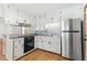 Well-lit kitchen features white cabinetry, stainless steel appliances, and a gray tiled backsplash at 16 S Church, Coats, NC 27521