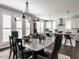 Open dining area with a stone-top table, elegant chandelier, white french doors, and a view of the modern kitchen at 1610 Draper View Loop # 101, Raleigh, NC 27608