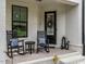 Inviting front porch features white brick, black trim, rocking chairs, and stylish decor, creating a cozy welcome at 1610 Draper View Loop # 101, Raleigh, NC 27608