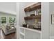 This bar area features floating wood shelves and glass storage with an open-concept view of the living room at 1625 Banks View Dr, Raleigh, NC 27603