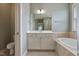 This bathroom features a soaking tub, neutral toned cabinets, and a tiled shower with a neutral paint color at 1962 Briar Chapel Pkwy, Chapel Hill, NC 27516