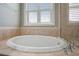 Close-up of a luxurious soaking tub with chrome fixtures, set against a backdrop of neutral tiling and natural light at 1962 Briar Chapel Pkwy, Chapel Hill, NC 27516