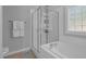 Bright bathroom featuring a tub with glass door shower, white tile, and neutral paint at 200 Holly Branch Dr, Holly Springs, NC 27540