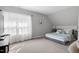 Bright bedroom with large window, neutral walls, carpet flooring, and comfortable bed with stylish blue and grey quilt at 200 Holly Branch Dr, Holly Springs, NC 27540