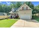 Inviting home with a two-car garage and a neatly manicured lawn, enhanced by mature trees in the background at 200 Holly Branch Dr, Holly Springs, NC 27540