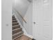 Carpeted staircase with a wooden handrail and neutral gray walls, complemented by wood flooring at 200 Holly Branch Dr, Holly Springs, NC 27540