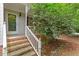 Close-up of a front porch with brick steps, white railings, and lush greenery providing privacy at 201 Cobblestone Dr, Chapel Hill, NC 27516