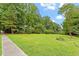 Large grassy yard surrounded by mature trees under a partly cloudy sky, conveying a sense of open space at 201 Cobblestone Dr, Chapel Hill, NC 27516