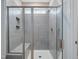 Modern tiled shower enclosure featuring glass doors, a built-in bench, and a rainfall shower head at 226 Faith Avenue, Sanford, NC 27330