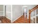 Inviting hallway with hardwood floors, neutral paint, and stairway with wood banister at 2309 King Malcolm Ln, Zebulon, NC 27597