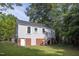 Two-story home with brick foundation and neutral siding, surrounded by lush green trees at 2423 Farthing St, Durham, NC 27704