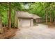 View of a single-story home featuring a two-car garage and gravel driveway, surrounded by lush greenery at 252 Fox Ridge, Pittsboro, NC 27312