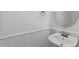 All-white half bath with round mirror and stylish sink with wainscoting, and modern fixtures at 2621 Asher View Ct, Raleigh, NC 27606