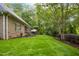 Expansive backyard featuring lush green lawn, a screened porch, mature trees, and an outdoor seating area at 3024 Weston Ct, Burlington, NC 27215
