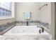 Jetted tub with decorative tile and a garden window allowing for natural light at 3024 Weston Ct, Burlington, NC 27215