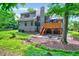 View of the backyard featuring a deck, patio, creek bed, grass, and wooded area at 306 Roebling Ln, Cary, NC 27513