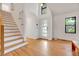Bright, modern foyer featuring a hardwood floor, a staircase with wood treads, and a modern glass-paneled front door at 306 Roebling Ln, Cary, NC 27513