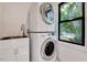 Bright laundry area featuring stacked washer and dryer, farmhouse sink, and subway tile backsplash at 306 Roebling Ln, Cary, NC 27513