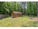 Backyard shed featuring wooden construction with a red roof and a small red bench at 3304 Black Stallion Ct, Zebulon, NC 27597