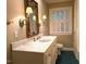 Bathroom vanity with marble countertop, decorative mirror, and sconce lighting at 3604 Woodlawn Rd, Rocky Mount, NC 27804