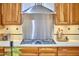 Close-up of a kitchen cooktop featuring wood cabinets, backsplash and white countertops at 3605 Laurel Creek Way, Durham, NC 27712
