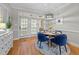 Bright dining room with hardwood floors, blue velvet chairs, stylish light fixture, and an open view to the porch at 4001 Falls River Ave, Raleigh, NC 27614
