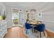 Bright dining room with hardwood floors, blue velvet chairs, stylish light fixture, and an open view to the porch at 4001 Falls River Ave, Raleigh, NC 27614
