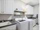 Laundry room featuring white cabinets, open shelving, modern washer and dryer at 4001 Falls River Ave, Raleigh, NC 27614