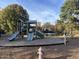 View of playground near lake, featuring slides, play structures, and a bench at 4001 Falls River Ave, Raleigh, NC 27614