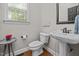 Charming powder room featuring hardwood floors, a pedestal sink, and natural light from a window at 4001 Falls River Ave, Raleigh, NC 27614