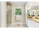 Bathroom featuring a tiled shower with glass enclosure, vanity with a granite countertop, and a window at 417 N Gurney St, Burlington, NC 27215