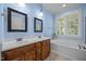 Bathroom featuring a double sink vanity, decorative mirrors and lights, and a large soaking tub at 44 Supreme Dr, Lillington, NC 27546