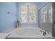 The bathroom offers a large soaking tub with jets, a window, tile flooring and a glass shower at 44 Supreme Dr, Lillington, NC 27546