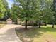 View of the home and detached garage, highlighted by a long driveway and mature trees at 44 Supreme Dr, Lillington, NC 27546